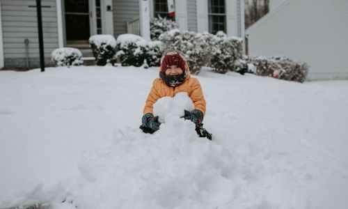 kid playing in snow pile
